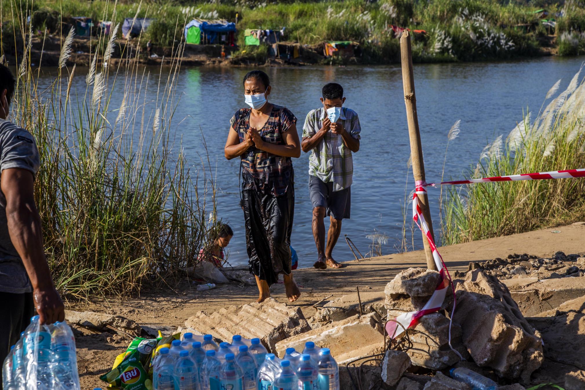 Displaced people from Karen State, who have been sheltering from Myanmar military attacks along the border, cross the river into Thailand to collect food donations. Picture by Athens Zaw Zaw. January 2022