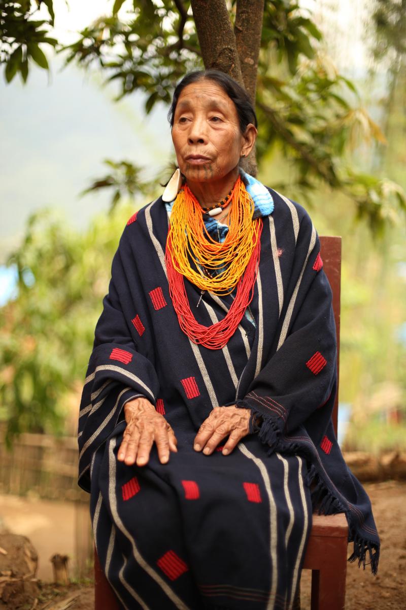 Cë̀kom wears her prized necklaces and a traditional blanket that she  wove herself