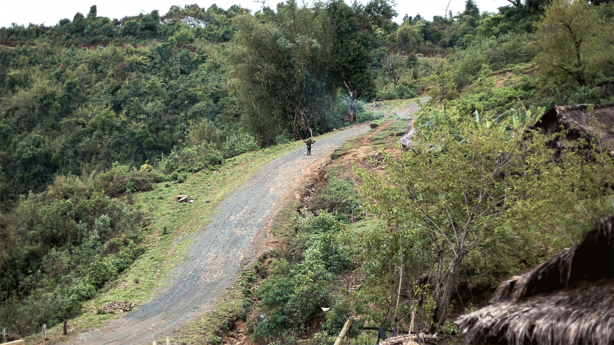 A hunter heads off into the forest from a village in the hills above Lahe