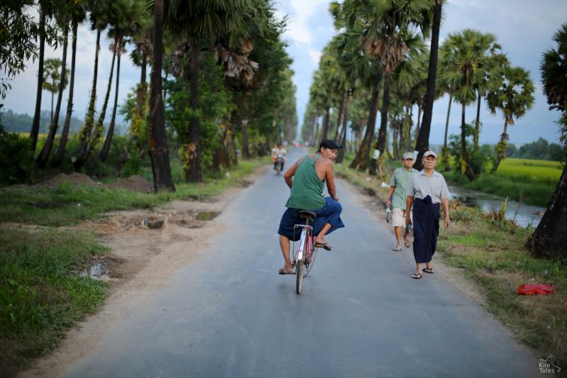 People take evening strolls on a tree lined road on the outskirts of Dawei